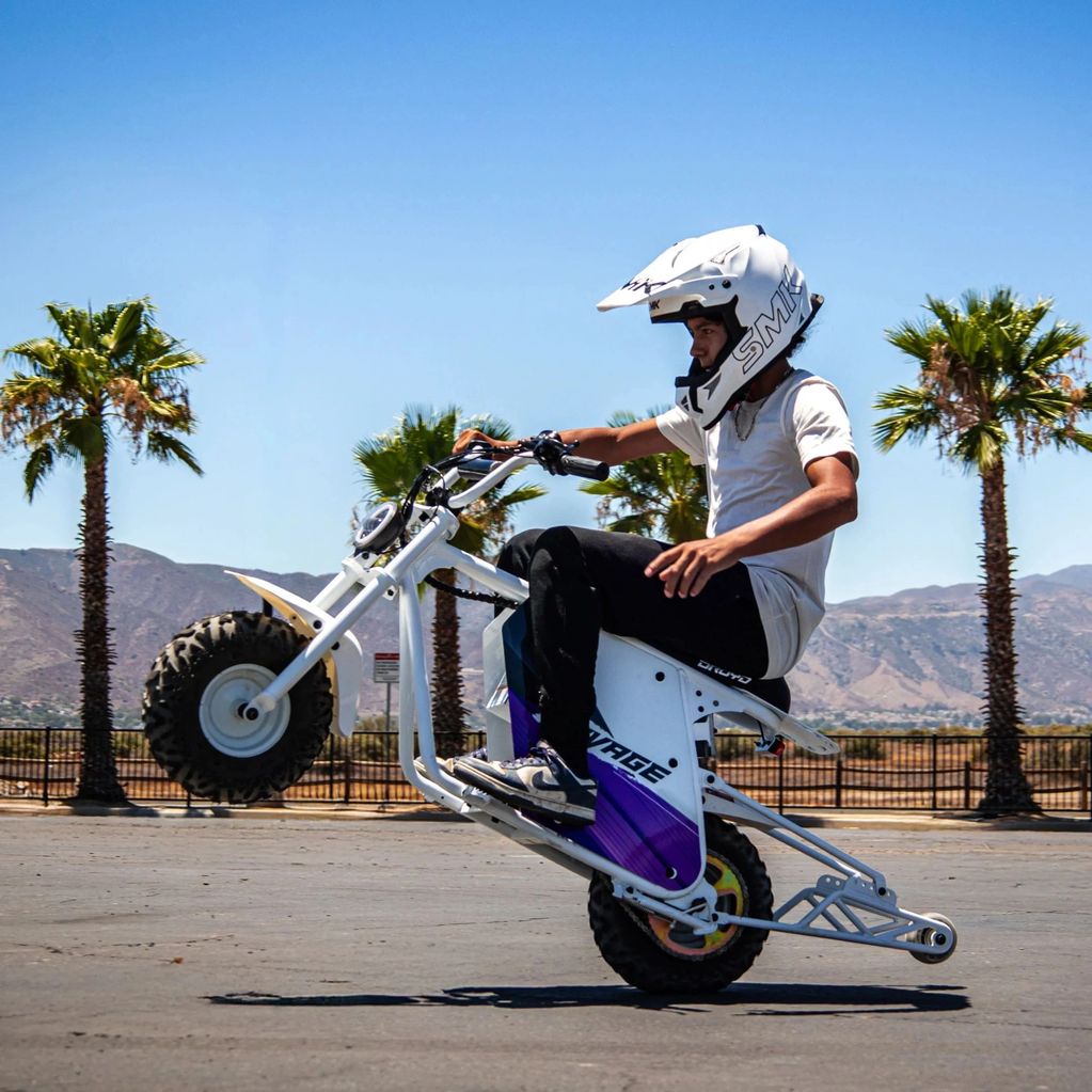 Person doing a wheelie on a motorbike in a sunny outdoor area.