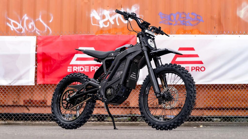 Black electric dirt bike against a red and white banner.