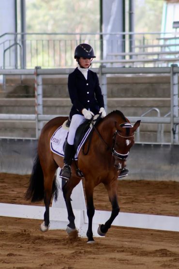Young rider in dressage competition on horseback.