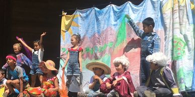 Children performing a colorful play on stage in costumes.