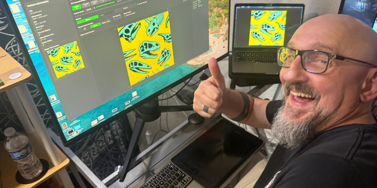 Man gives thumbs up while working on dinosaur skull pattern designs on screens.