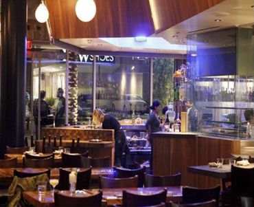 Cozy restaurant interior with wooden tables, chairs, and warm lighting.