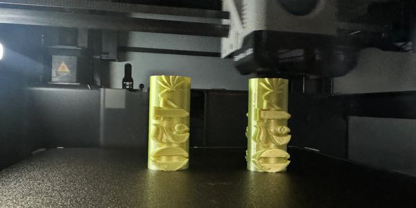 Two yellow 3D-printed objects inside a 3D printer.