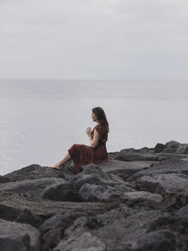 woman meditation on rocks by the ocean
