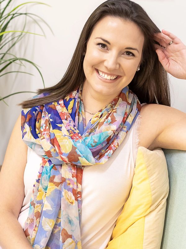 Smiling woman wearing a colorful floral scarf relaxing indoors.