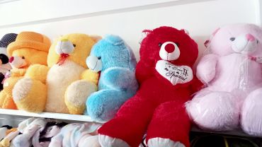 Colorful teddy bears lined up on a shelf.