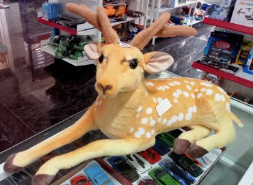 Large plush deer toy on a glass table.