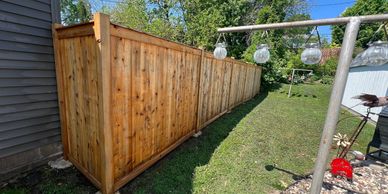 A long wooden fence beside a house under a clear blue sky.