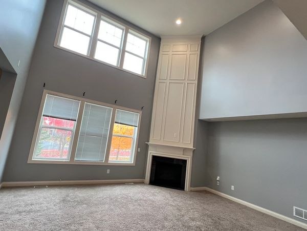Spacious living room with high ceilings and fireplace.