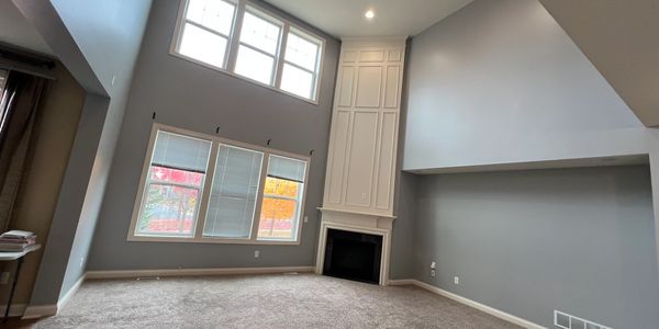 Spacious living room with high ceilings and fireplace.