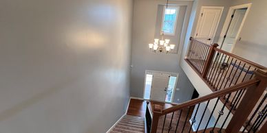 Modern stairwell with wooden banister and chandelier lighting.