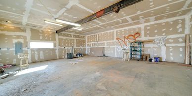 Empty unfinished garage with graffiti on drywall walls.
