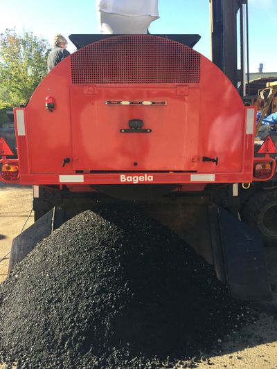 Red Bagela machine with black material piled underneath.