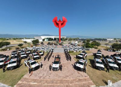 Formación de policías frente a una gran escultura roja al aire libre.