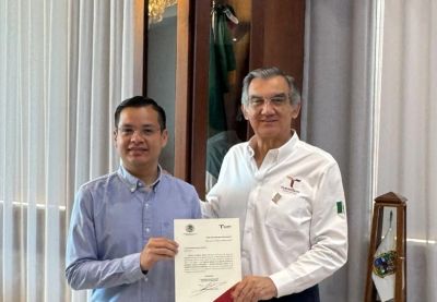 Dos hombres posan con un documento oficial.