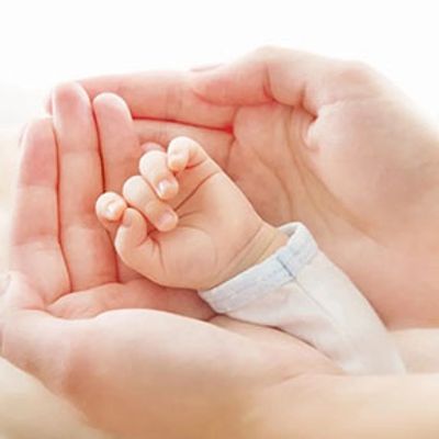 Adult hands holding an infant's hand