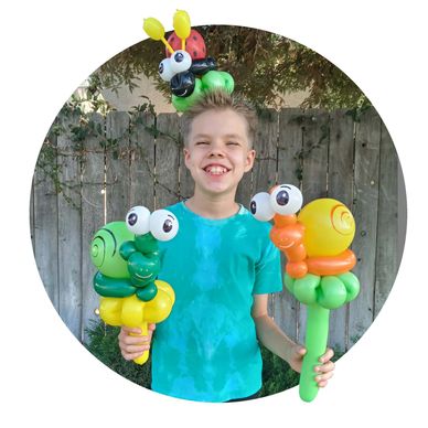 Boy holding colorful balloon snails outdoors.