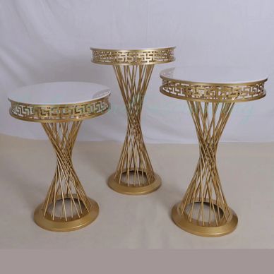 Set of three gold and white decorative pedestal tables.