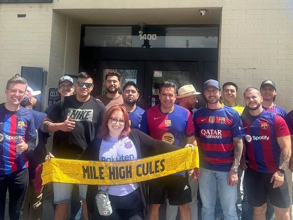 Group of soccer fans holding a "Mile High Cules" scarf.