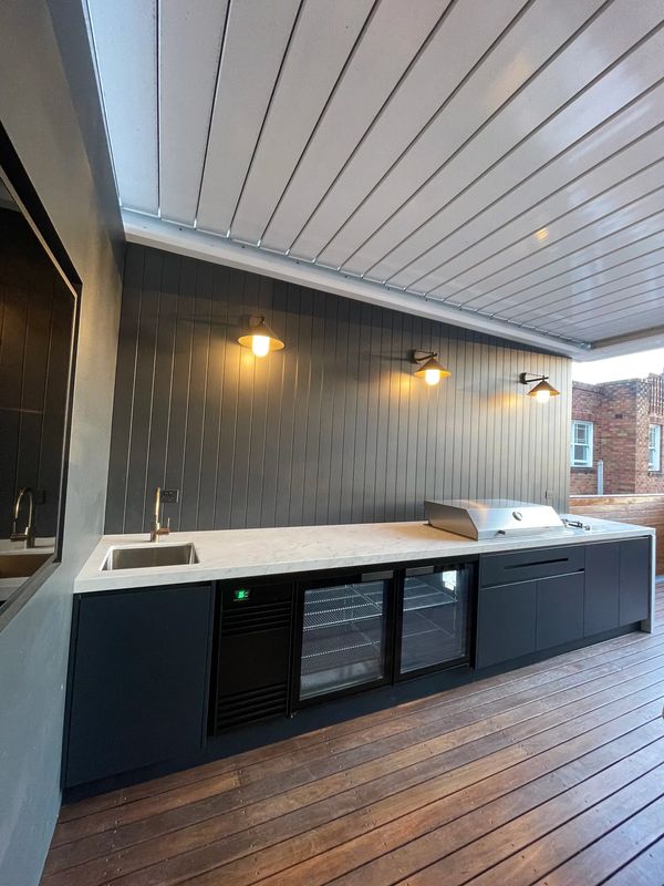Modern outdoor kitchen with black cabinets, marble countertop, and built-in grill.