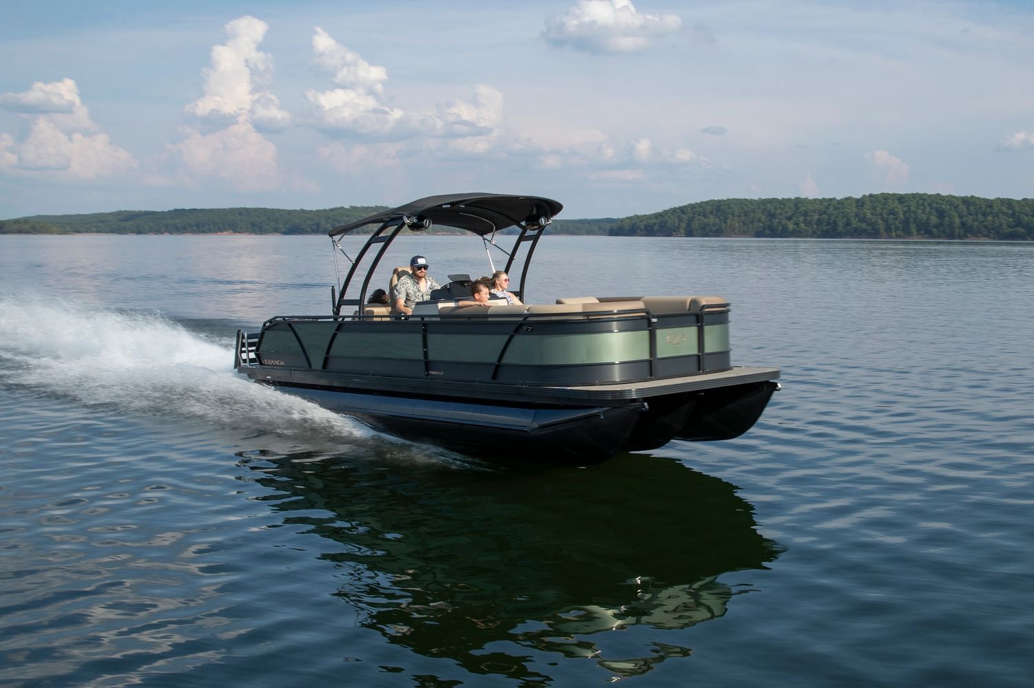 A sleek pontoon boat cruising on a calm lake with three passengers.