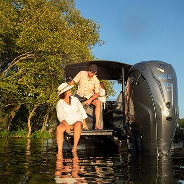A couple relaxing on a boat with feet in the water during sunset.