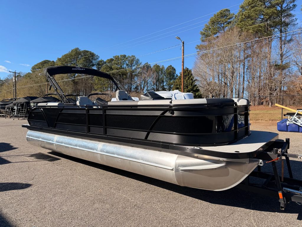 Black and silver pontoon boat parked on a trailer under clear blue sky.