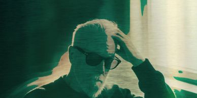 Man wearing sunglasses, touching his hair with a contemplative look.