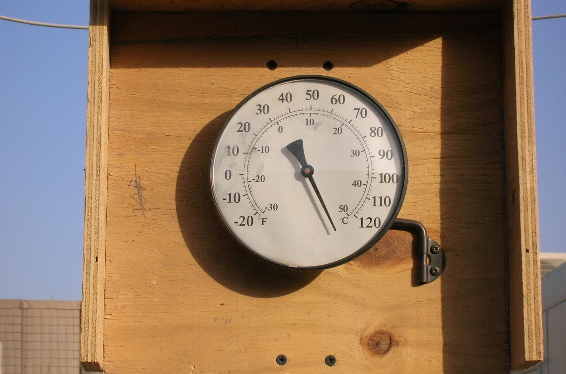 Outdoor thermometer mounted on wooden board.