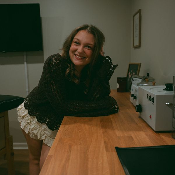Smiling woman leaning on a wooden counter in a cozy room.