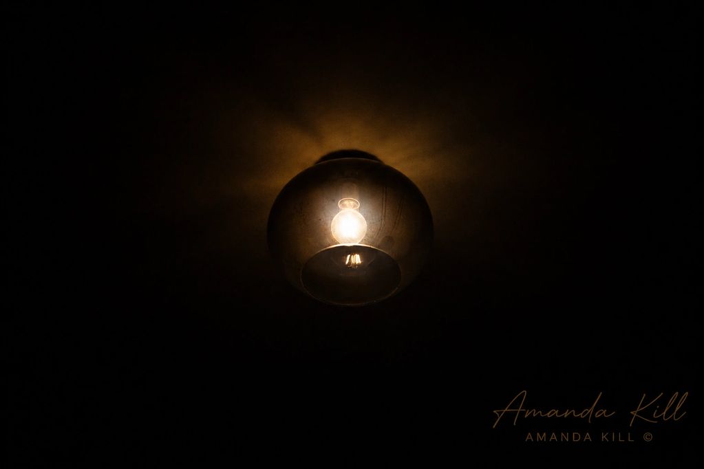 A glowing light bulb inside a glass fixture in a dark room.