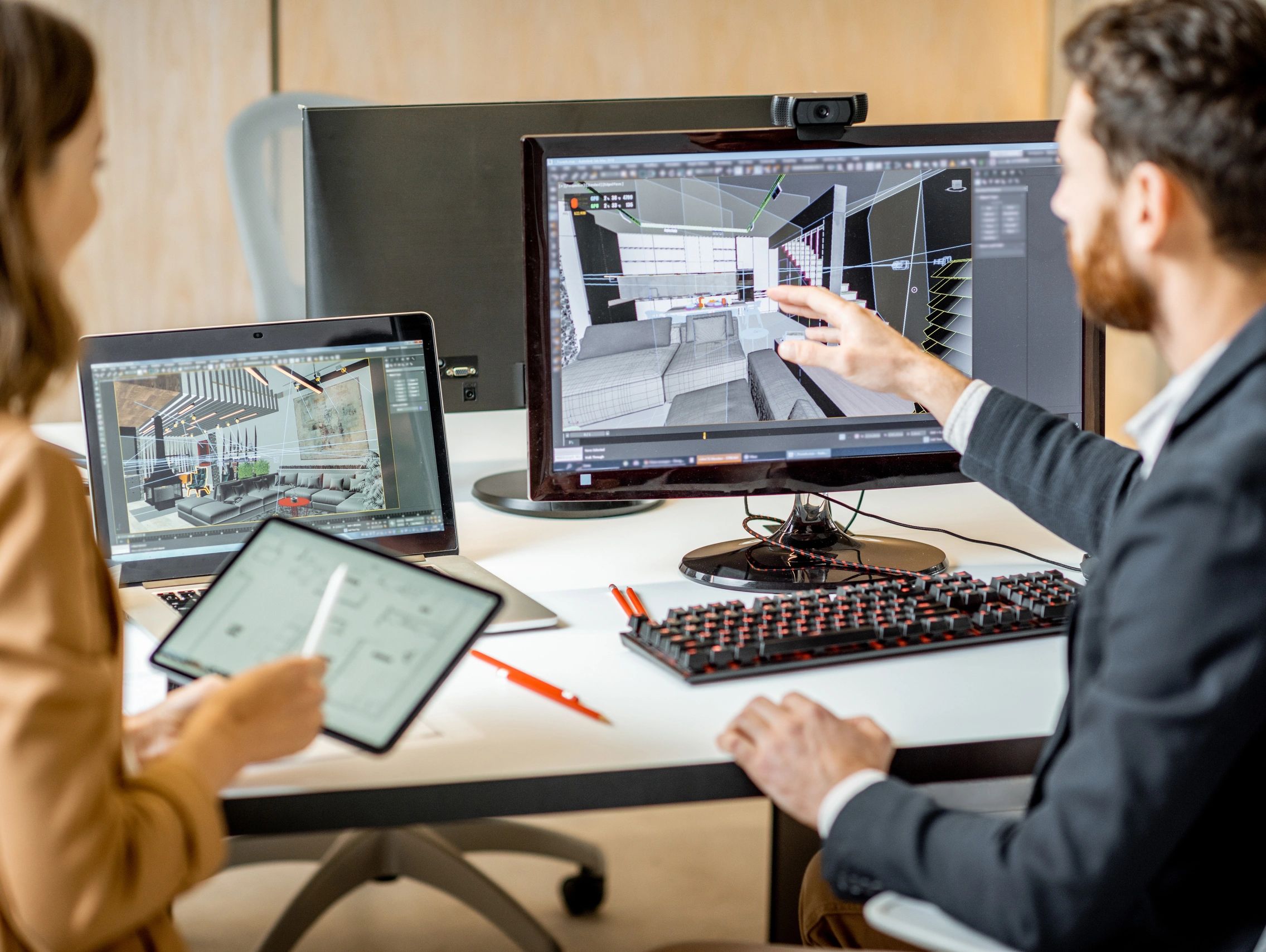 Two architects discussing 3D interior designs on screens and tablet.