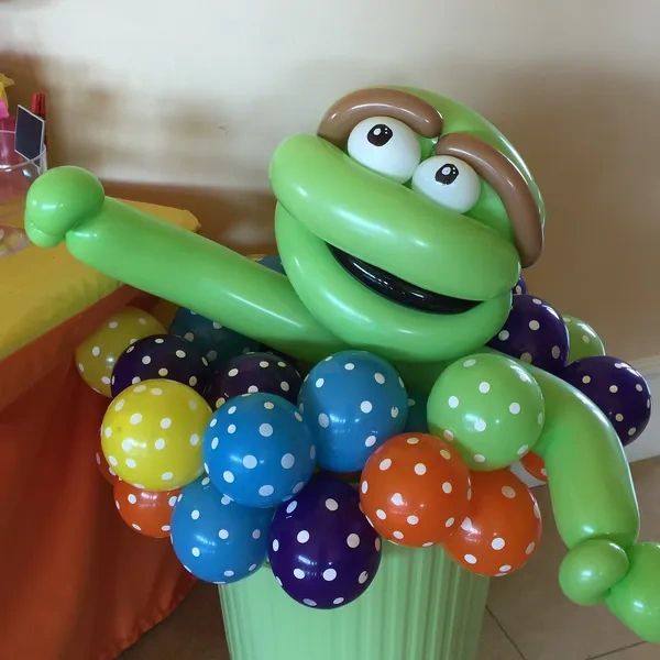 Oscar the grouch balloon animal in a trash can full of colorful balloons.