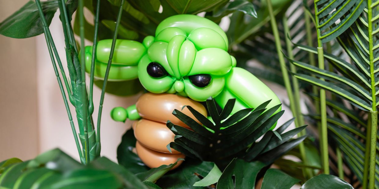 A balloon sculpture of Yoda hidden among green plants.