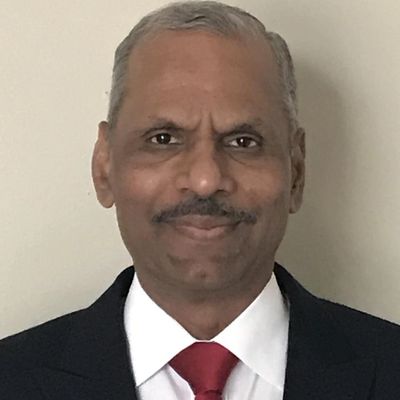 Portrait of a man in a suit with a red tie smiling gently.