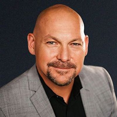 Smiling bald man in a gray suit jacket.