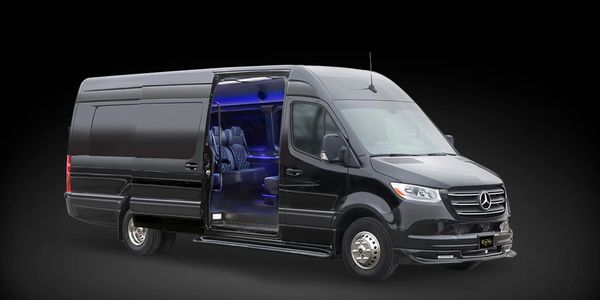 Black luxury Mercedes van with illuminated interior and open door.