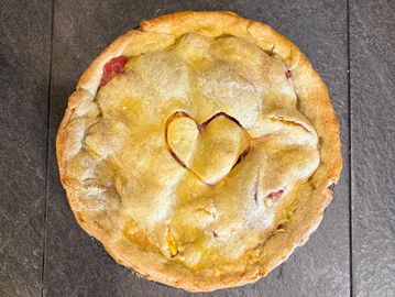 A freshly baked pie with a heart-shaped decoration on top.