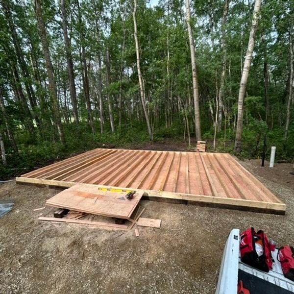 Wooden base frame for a structure in a forest clearing.