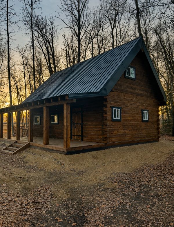 Wooden cabin in a forest at sunset.