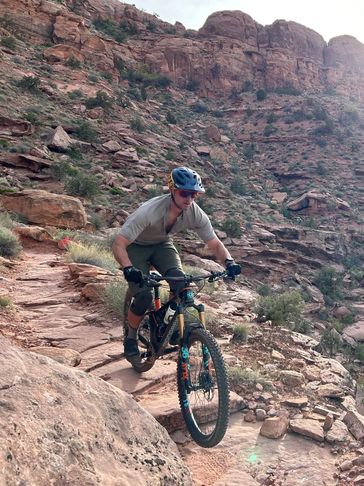 Mountain biker navigating a rocky trail in a desert landscape.