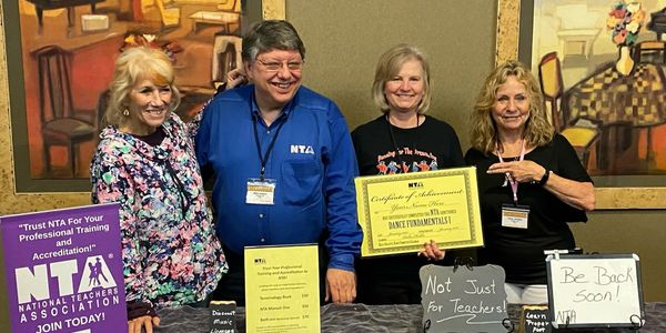 Group of four people smiling with NTA certificates and signs.
