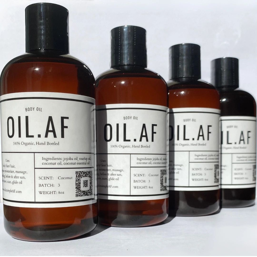 Four bottles of OIL.AF 100% organic body oil with coconut scent, arranged in a row.