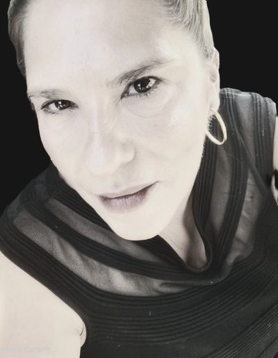 Close-up portrait of a woman with hoop earrings in a black top.