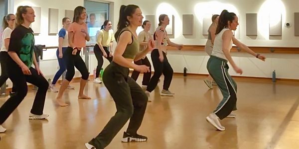 Group of people energetically dancing in a studio.