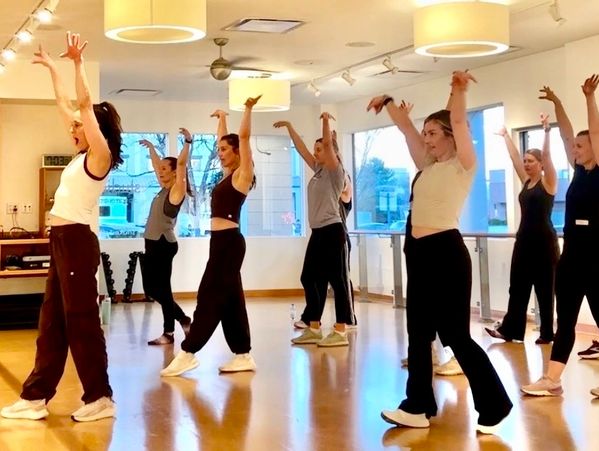 A group dance class practicing choreography in a bright studio.