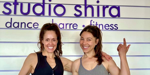 Two women smiling inside Studio Shira dance and fitness studio.