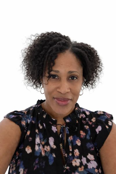 Portrait of a woman with curly hair wearing a floral blouse.