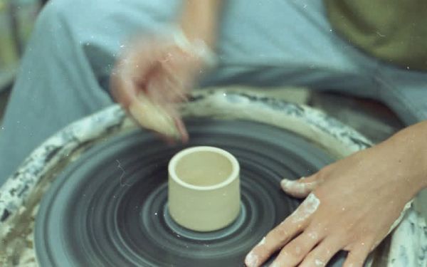 Person shaping clay on a pottery wheel.