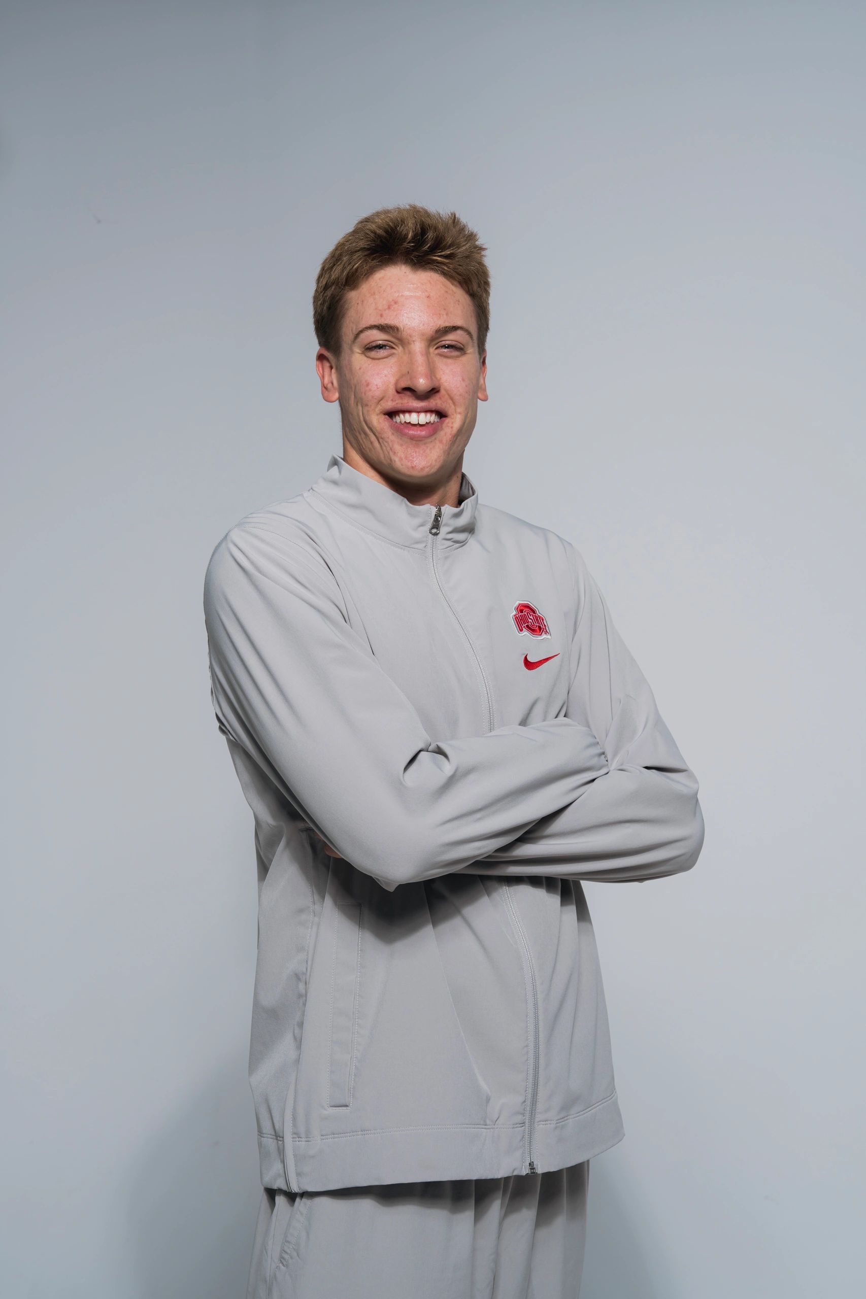 Young man in gray Ohio State jacket smiling.